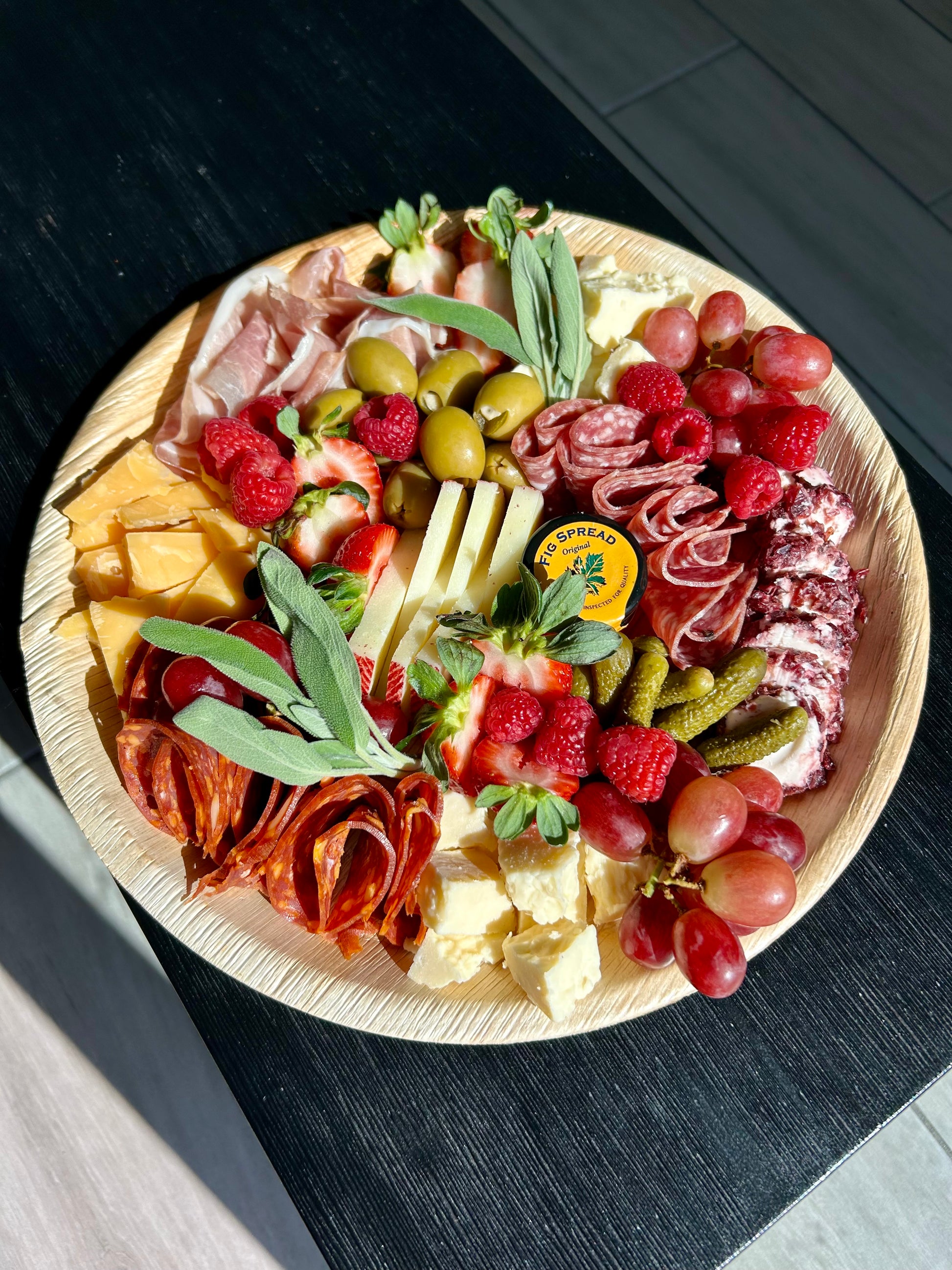 charcuterie board with meats, cheeses, and fruits on a wooden board.
